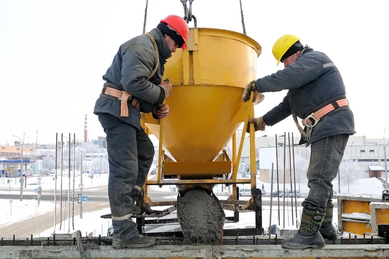 construction building workers at construction site pouring concrete in form