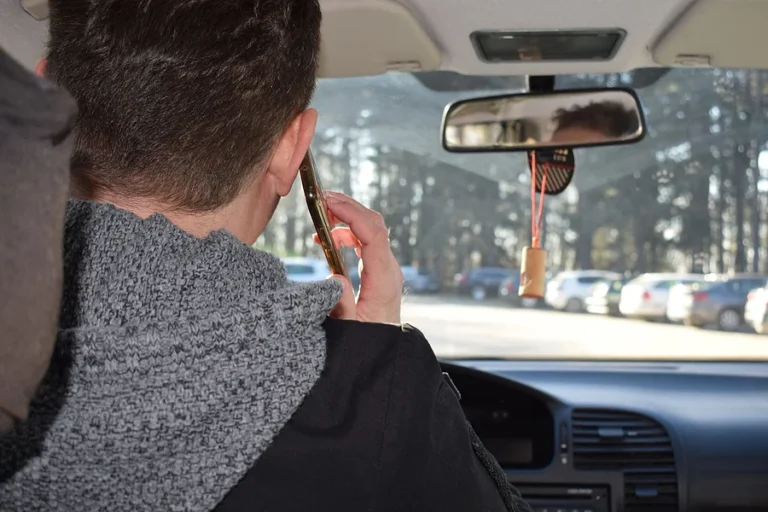 A man is talking on the phone while driving a car. Dangerous driving and a high possibility of a car accident.