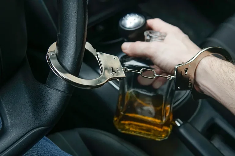 Man in handcuffs holds bottle of alcohol in car. Drunk driving concept. Dont drink and drive.