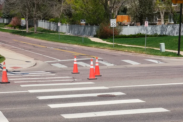 Orange road construction safety traffic cones during road repair construction maintenance work at crossroads intersection with crosswalk city street view photo.