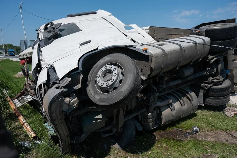 The truck is lying on its side in a car accident on the highway