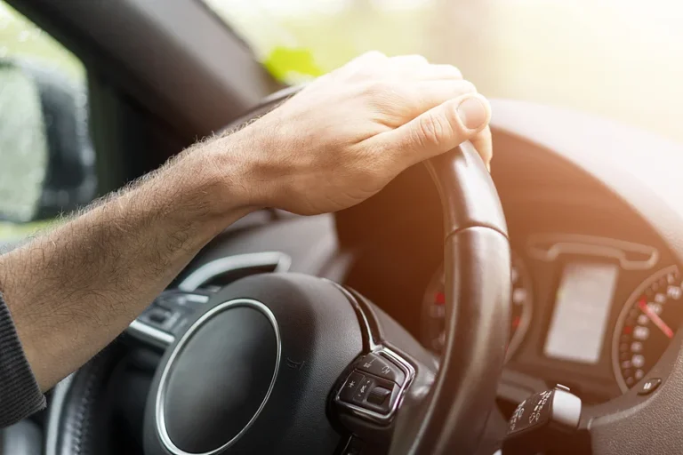 Male hands holding car steering wheel. Hands on steering wheel of a car driving. Young Man driving a car inside cabin. Multimedia system. Man Traveling In Self Driving Car. Car inside.