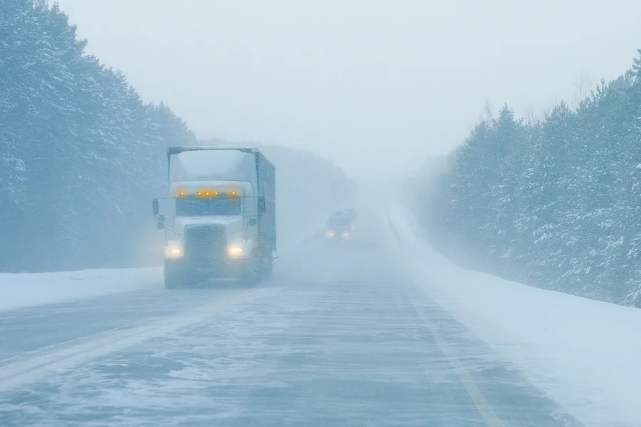 Trucks and cars on the road in a snow storm. Snowfall on the road. A storm warning.