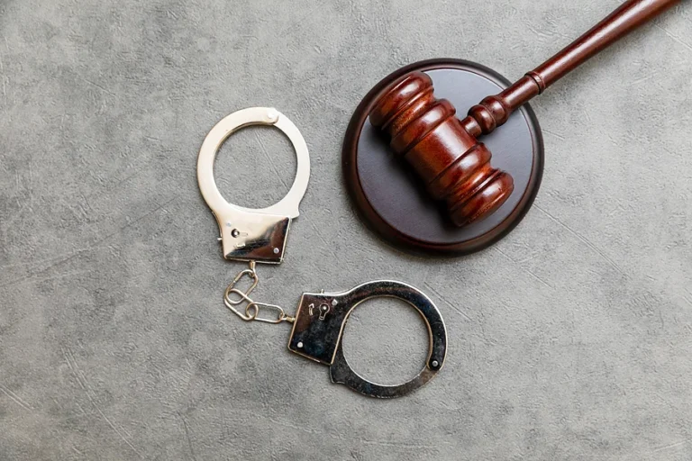 Law theme. Court of law trial in session. Judge gavel handcuffs on grey table in lawyer office or court session. Mallet of judge on concrete stone grey background. Justice human rights concept