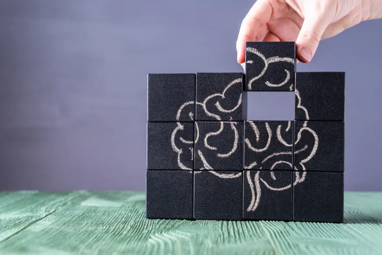 The concept of the human brain. Education, science and medical concept. Brain drawn in chalk on black cubes. Female hands put in place the last element of the puzzle.