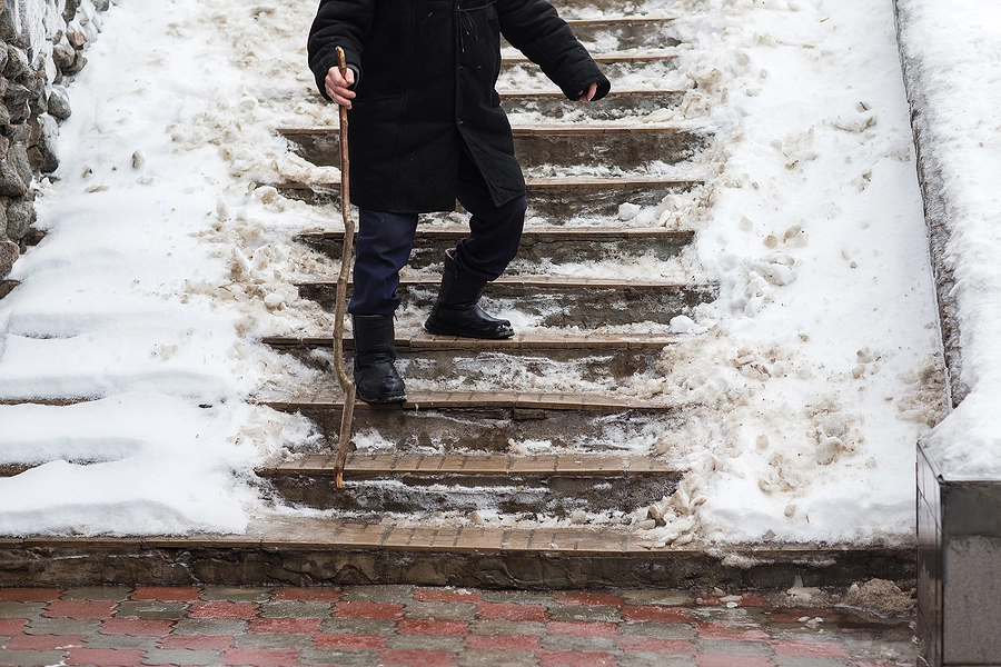 man with a cane navigating icy steps after a snow storm in north dakota about to slip and fall